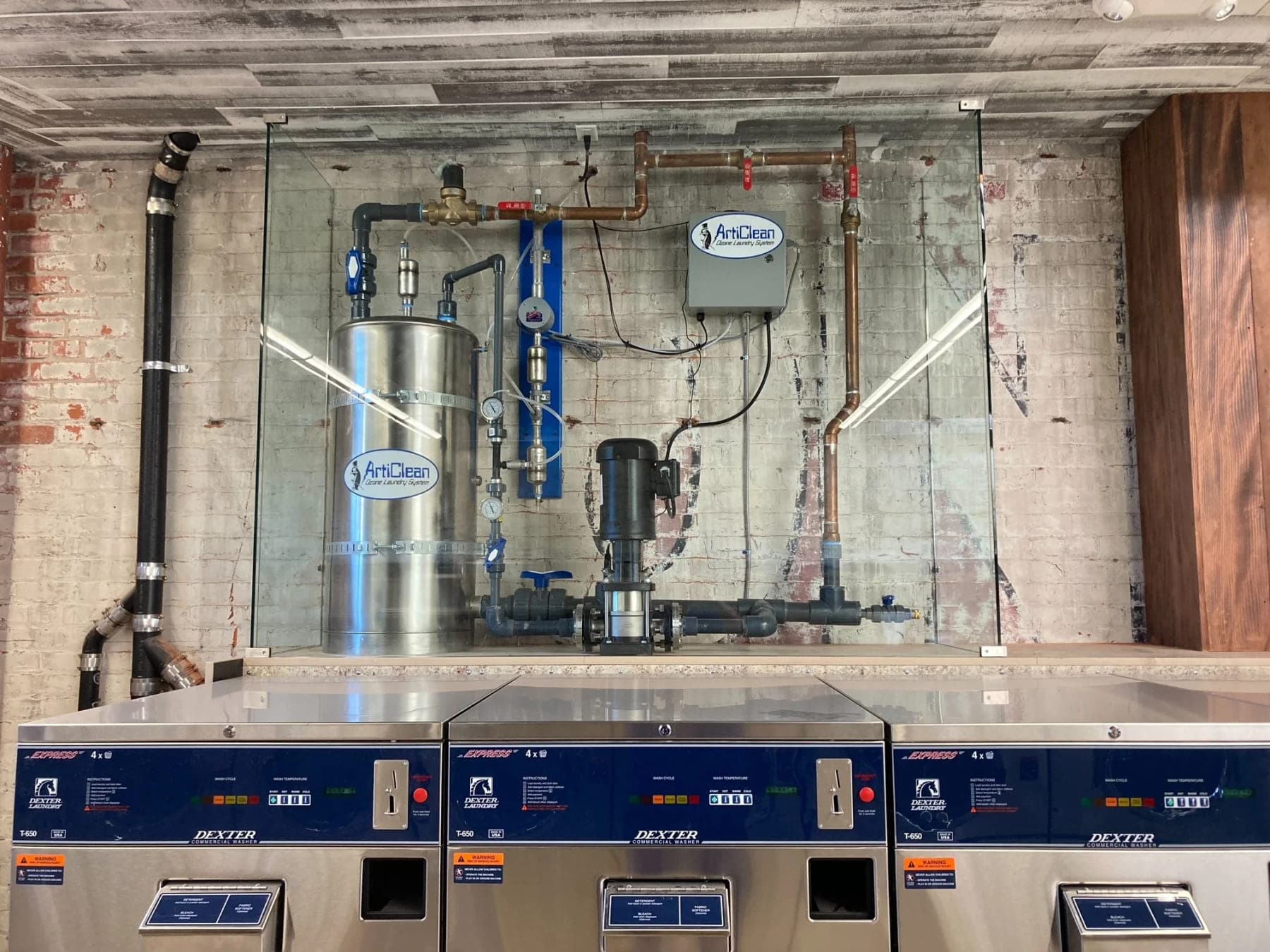 Stainless steel ozone contact tank and circulation pump installed above a bank of commercial washers