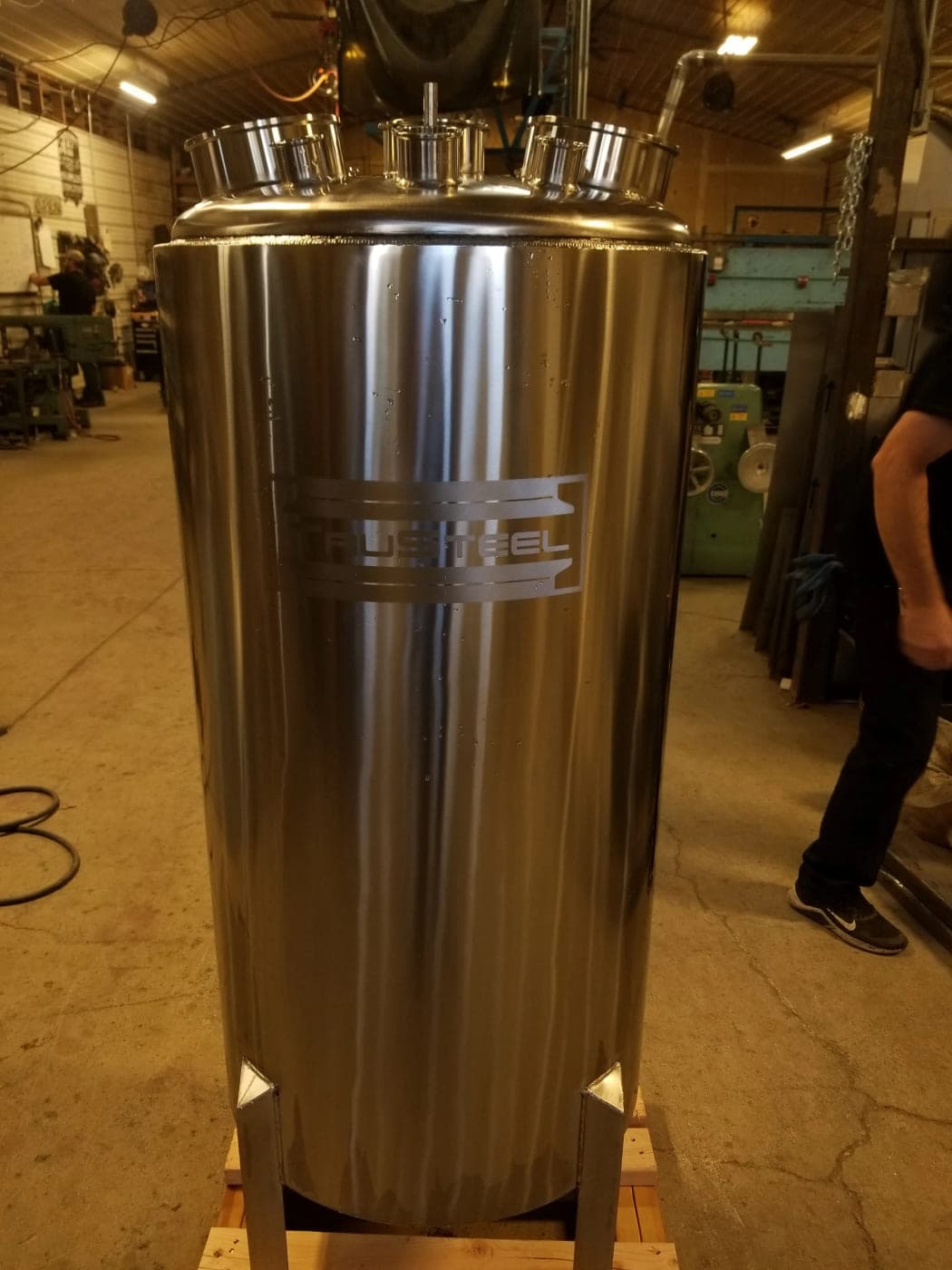Polished vertical stainless steel vessel with multiple large ferrule ports on the domed top