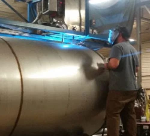 Swhift fabricator finishing the shell of a large horizontal stainless steel tank
