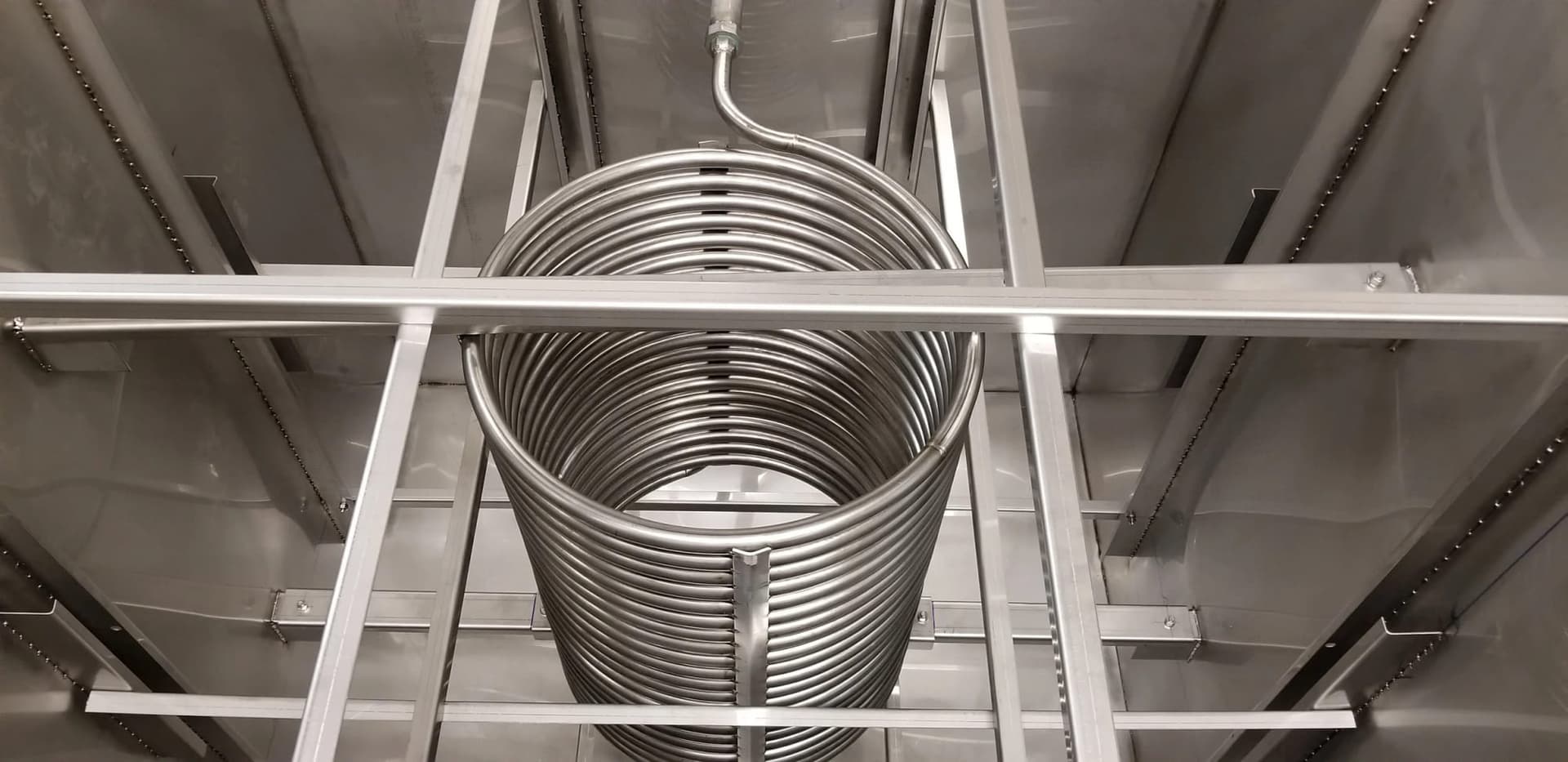 Stainless steel heat exchange coil mounted on welded support rails inside a tank
