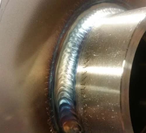 Close-up of a continuous TIG weld bead where a fitting joins a stainless steel tank